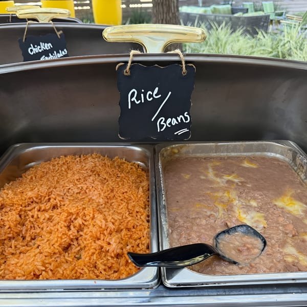 Chafing dishes with rice, beans, and chicken enchiladas, labeled with small chalkboards.